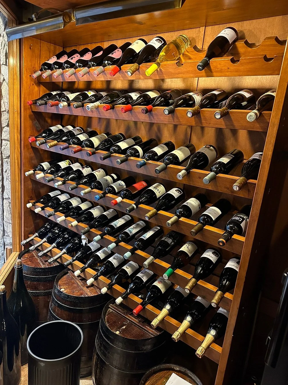 Pared de botellas de vino y barricas en Bodega Azor
