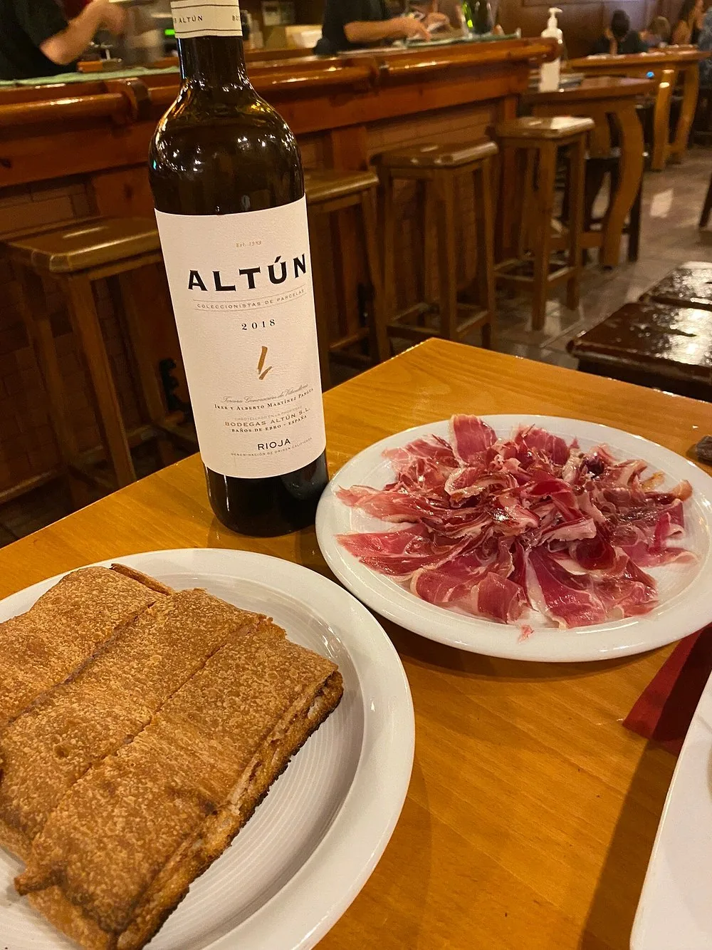 Jamón ibérico al corte con botella de vino en la barra